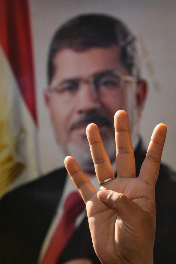 Le signe de rabia, devant le poster de l'ancien président Mohamed Morsi le 18 juin à Istanbul. Photo AFP