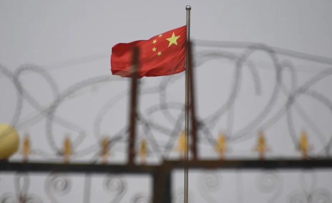 Le drapeau chinois flotte derrière des barbelés dans une cité de Yangisar, au sud de Kashgar, dans la région occidentale du Xinjiang en Chine (4 juin 2019). Greg Baker/AFP