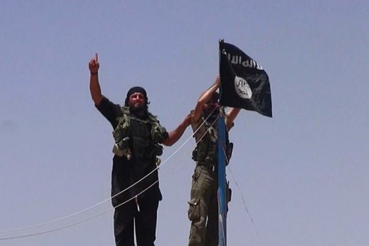 Des combattants de l'Etat islamique en Irak et au Levant (EIIL) hissent leur drapeau à un poste frontière entre l'Irak et la Syrie, le 11 juin. | AFP/LeMonde.fr