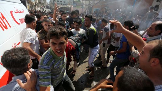 Des Palestiniens prennent en charge un des corps des personnes tuées lors du raid israélien, ce vendredi 27 juin 2014 à Gaza. [MOHAMMED SABER - Keystone], rts.ch