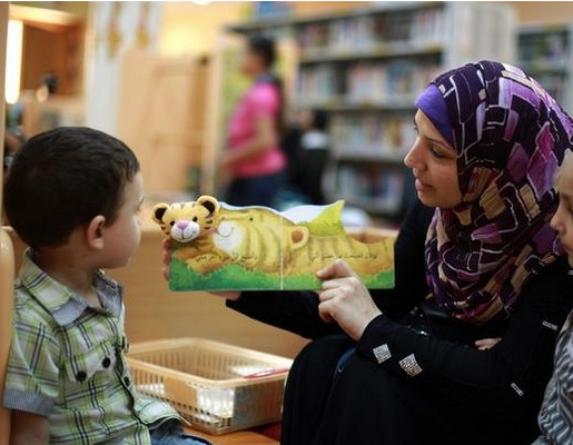 Une mère palestinienne lit une histoire à ses enfants lors d’un atelier de lecture estival (AFP)
