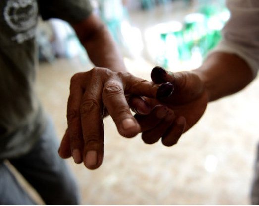 Un fonctionnaire électoral aide un électeur à appliquer de l’encre sur son doigt, dans un bureau de vote à Kuta, sur l’île touristique indonésienne de Bali, le 9/12/2015. L’Indonésie est la plus grande démocratie à majorité musulmane au monde.